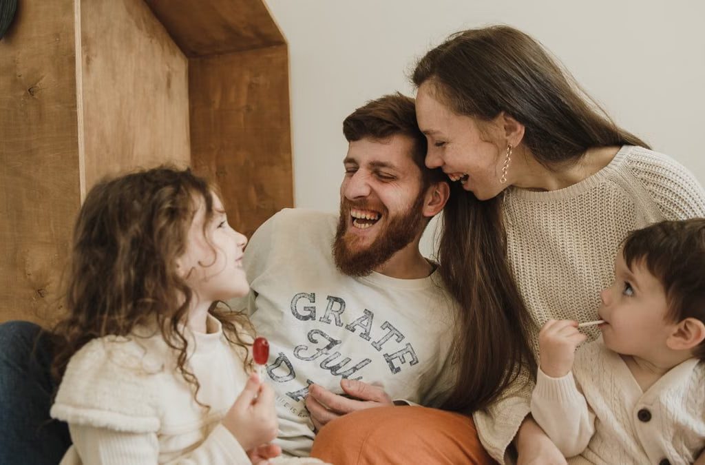 Happy family enjoying quality time with their children indoors, sharing laughter and joy.