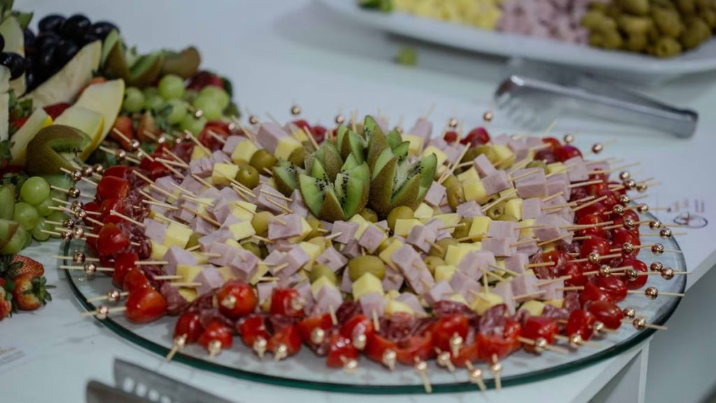 Vibrant platter of fruit and cheese skewers with kiwi, olives, and tomatoes, perfect for snacking.